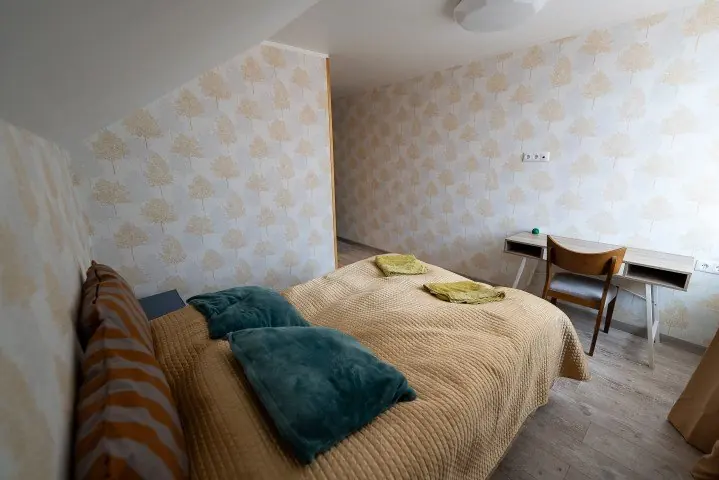 Host house bedroom with a double bed and desk in the attic