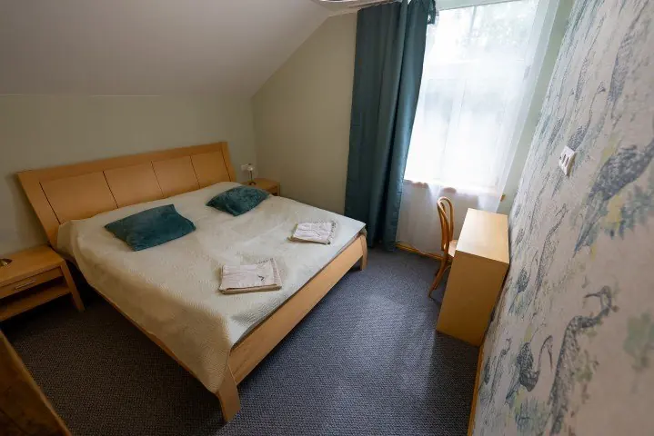 Bright host house bedroom with a wooden bed and green curtain