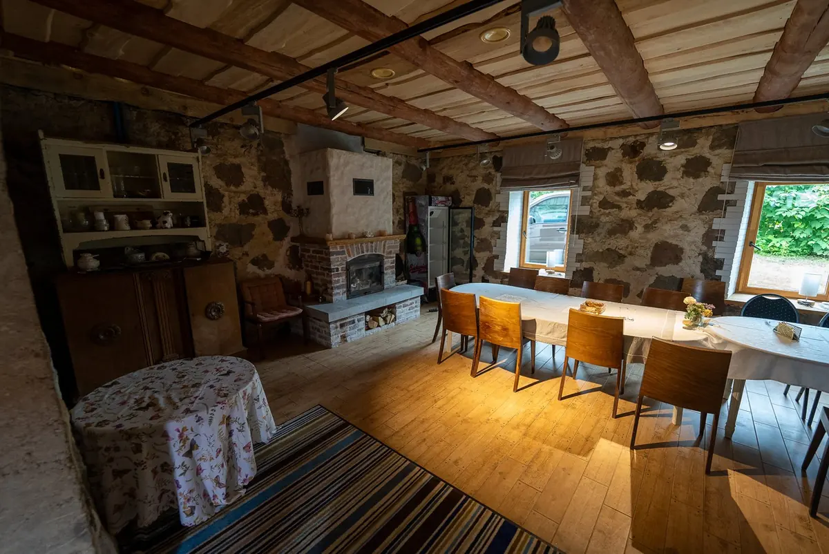 The spa building's fireplace hall with stone walls, wooden beams and a long table