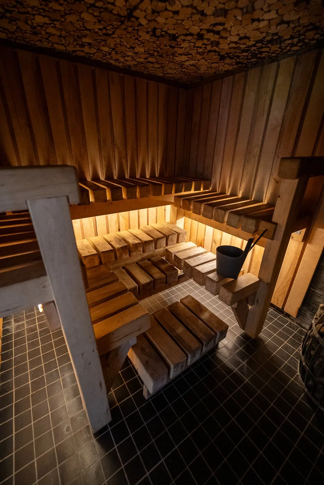 Wood-fired sauna with multi-level wooden benches and warm light