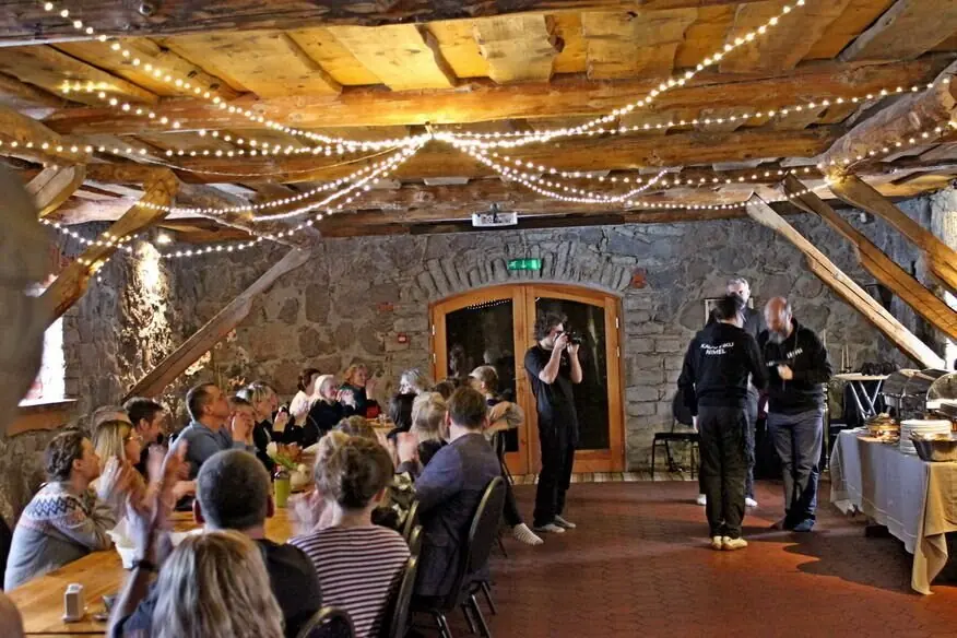 A party in a hall decorated with lights, guests at tables and on the dance floor