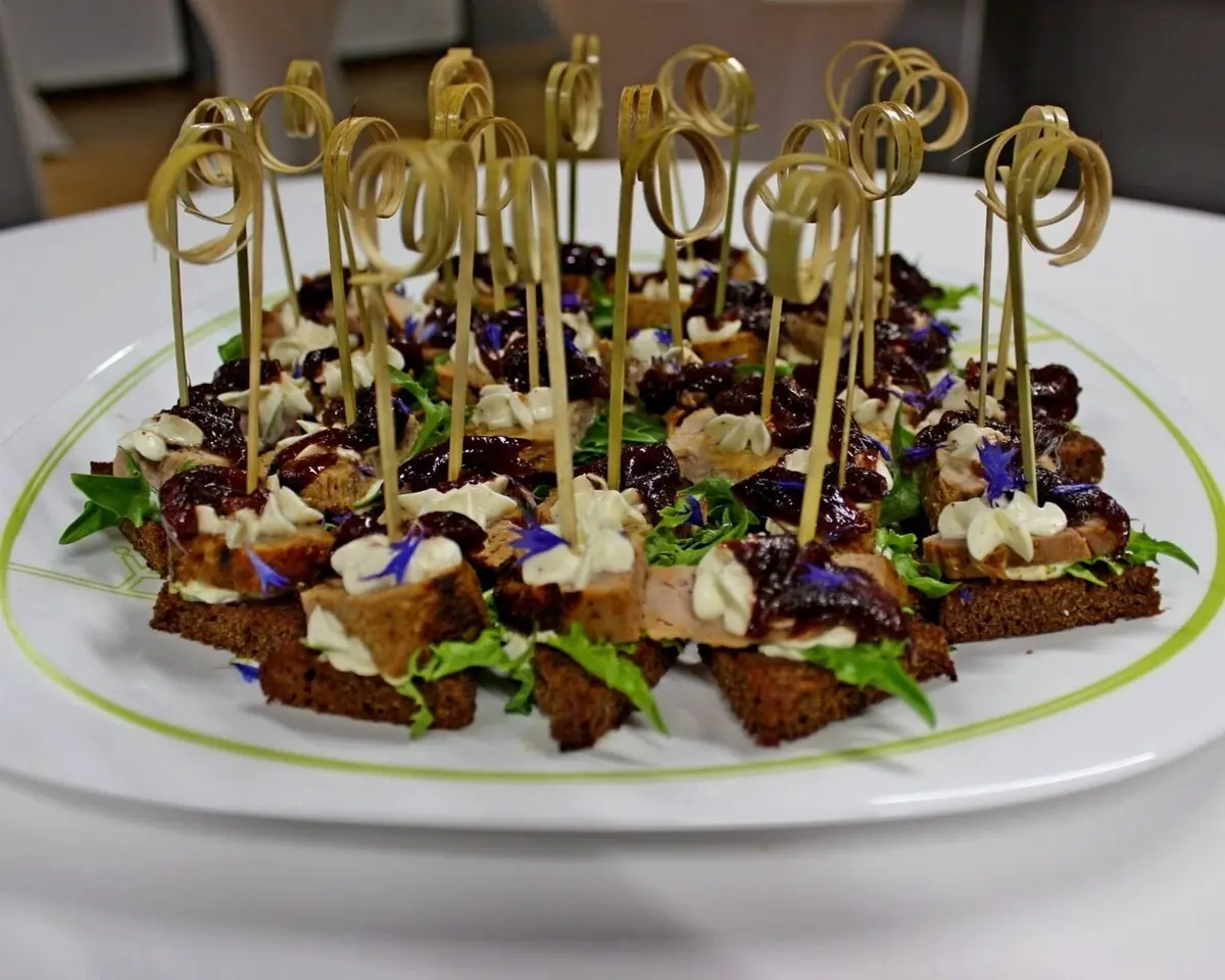 A platter of rye bread canapés with edible flowers and herbs